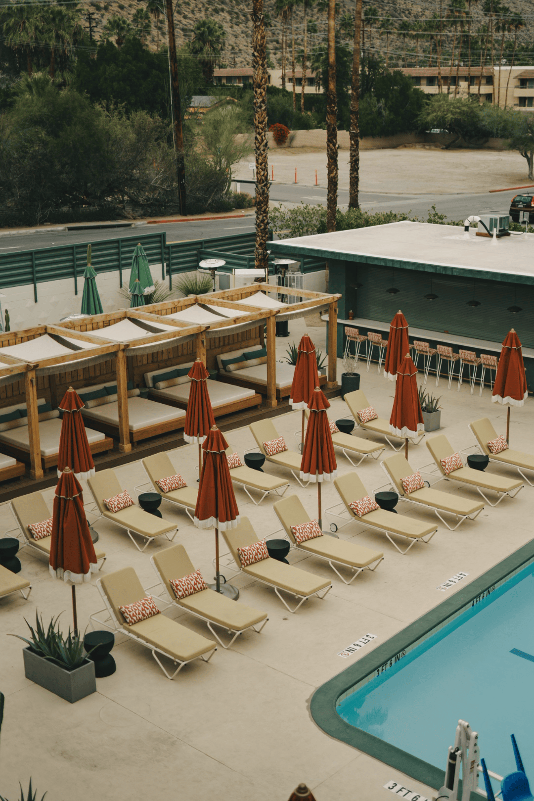 Full-color architectural photograph of a boutique hotel pool deck with lounge chairs and desert mountains beyond