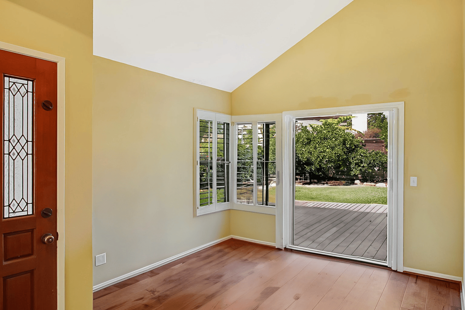 Full-color interior photograph of a sunroom entry with vaulted ceiling and stained glass door