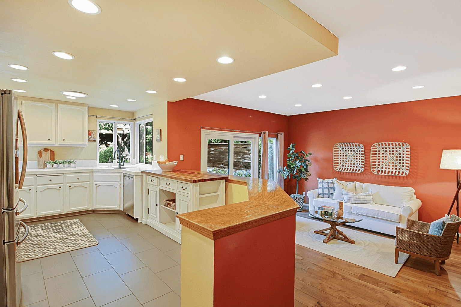 Full-color interior photograph of an open kitchen and living room with warm-toned walls