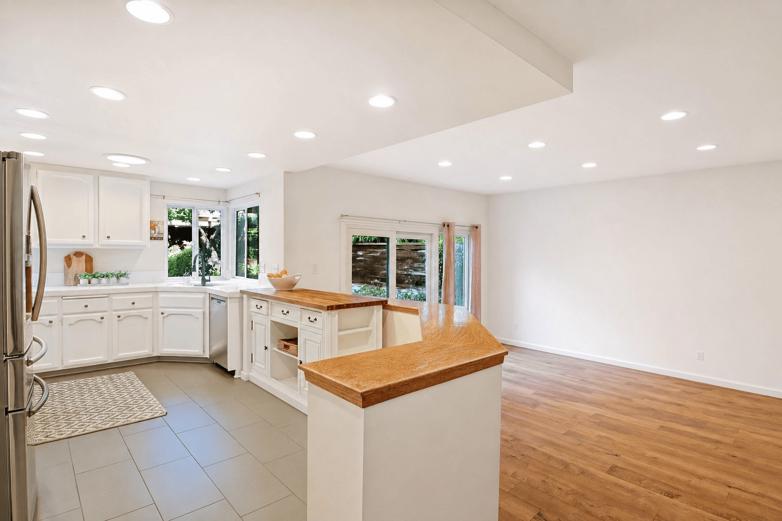 Full-color interior photograph of an open-concept kitchen repainted white for a listing