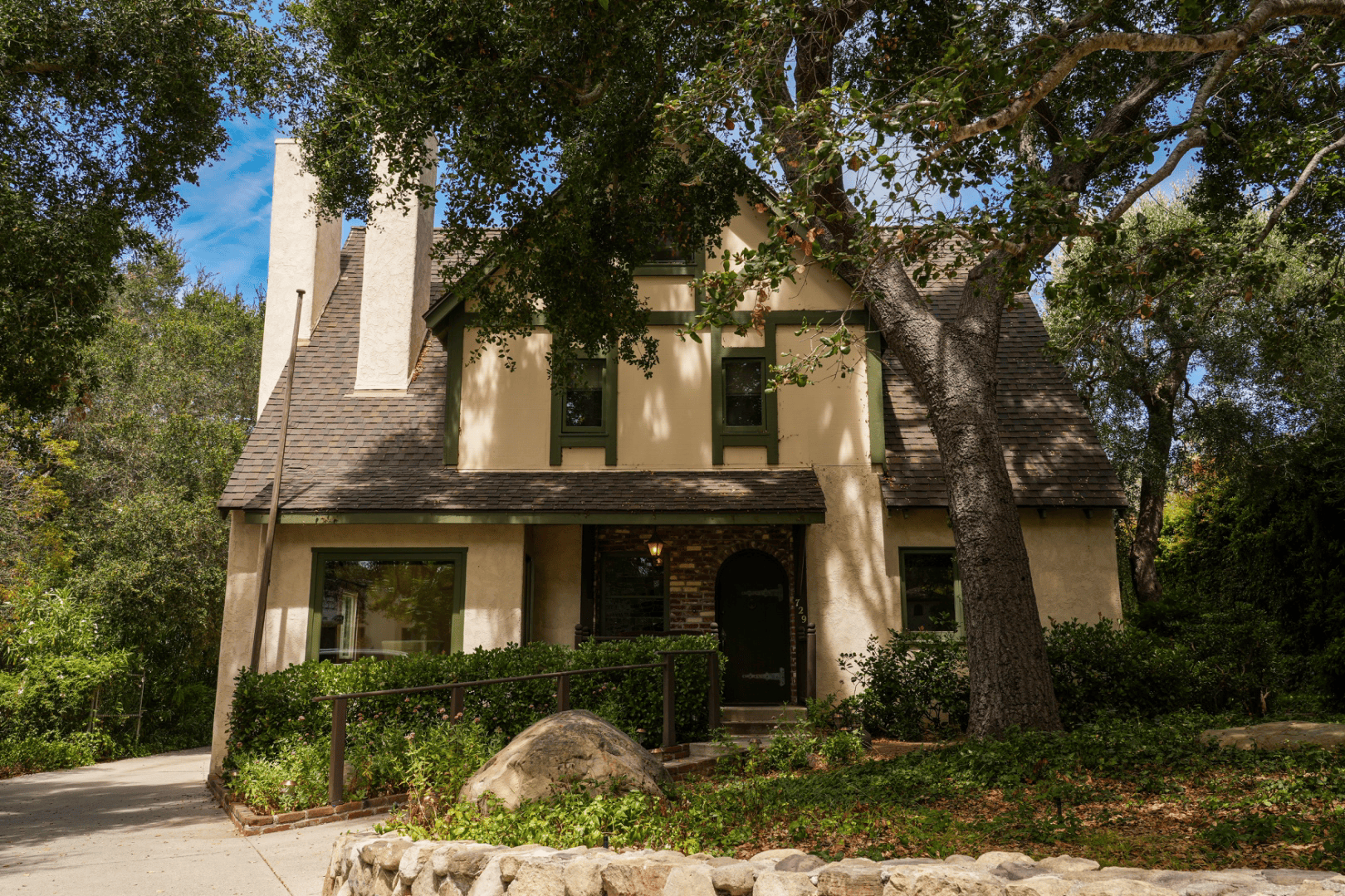 Tudor-style Santa Barbara home exterior framed by mature oak trees, full-color architectural photograph