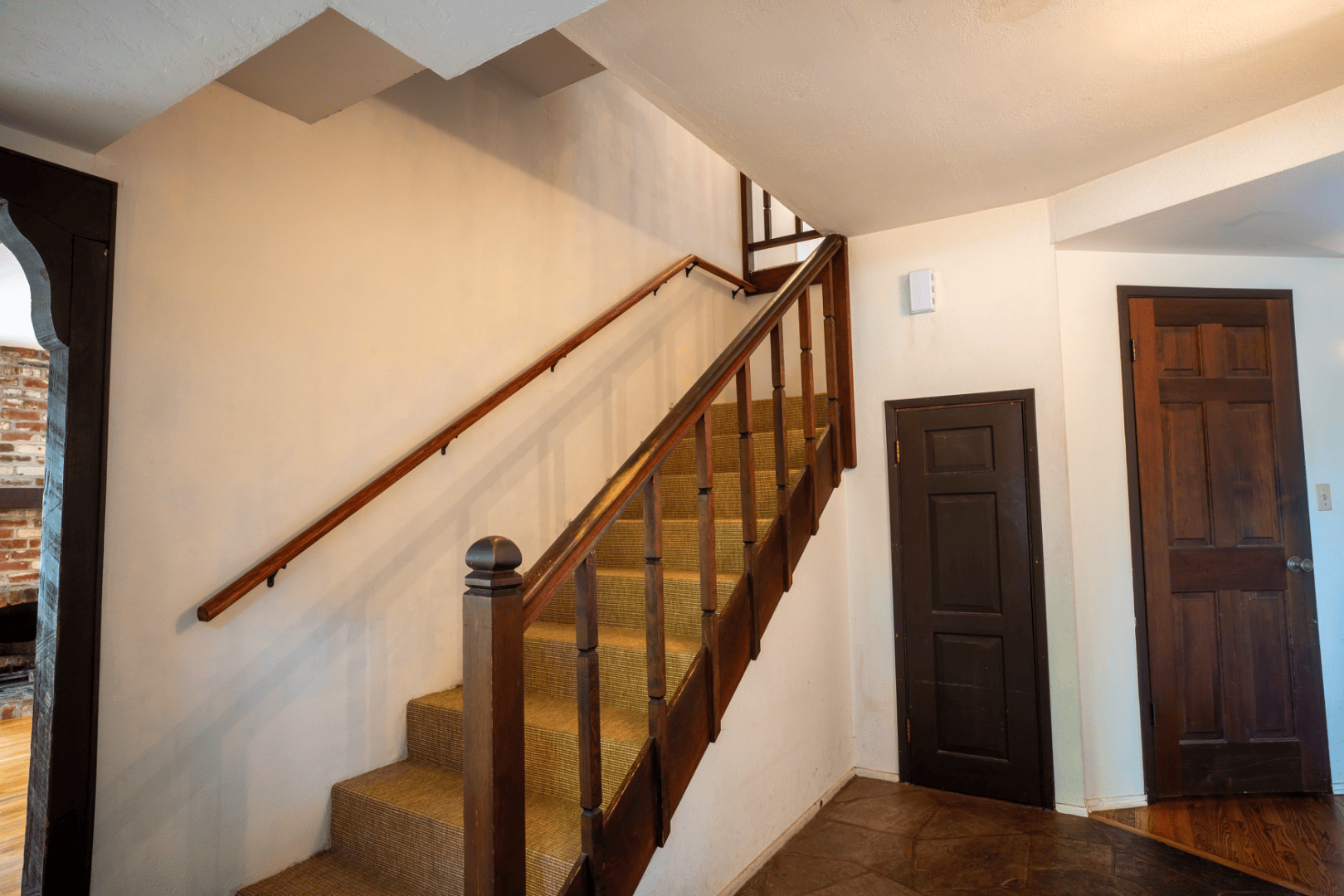 Wood staircase with carpet runner and paneled doors off the entry hall, full-color interior photograph