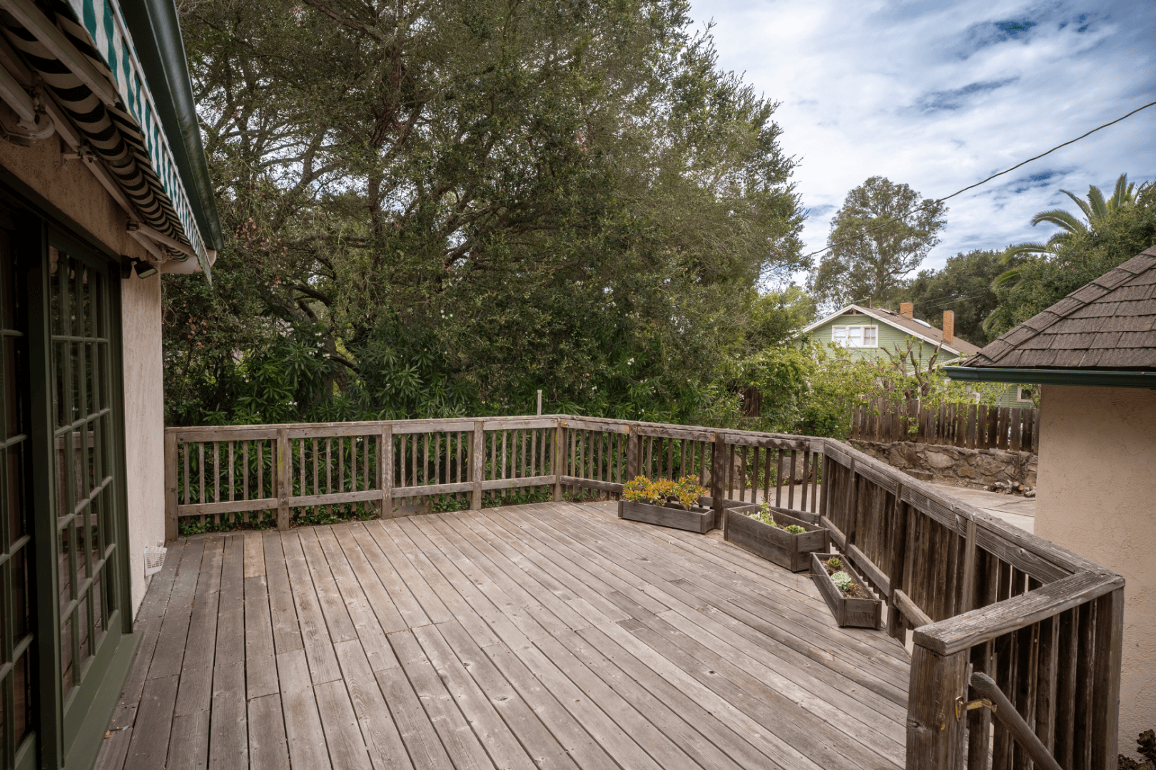 Wraparound wood deck with built-in planters overlooking mature oak trees, full-color exterior photograph