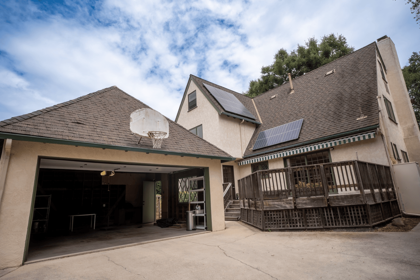 Rear exterior with two-car garage, basketball hoop, and mountain backdrop, full-color architectural photograph