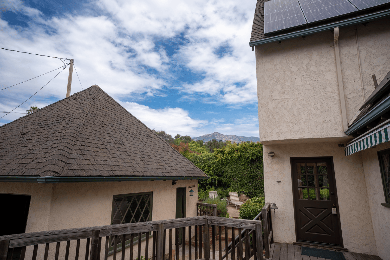Side deck with solar panels and mountain view beyond the property line, full-color exterior photograph