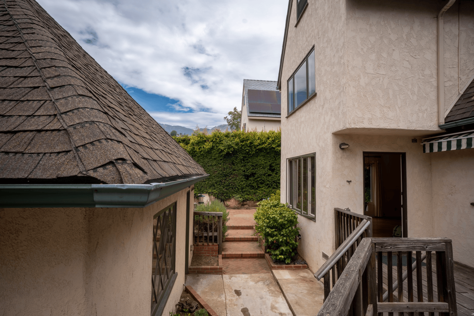 Side yard brick walkway between stucco walls leading to a private deck entrance, full-color architectural photograph