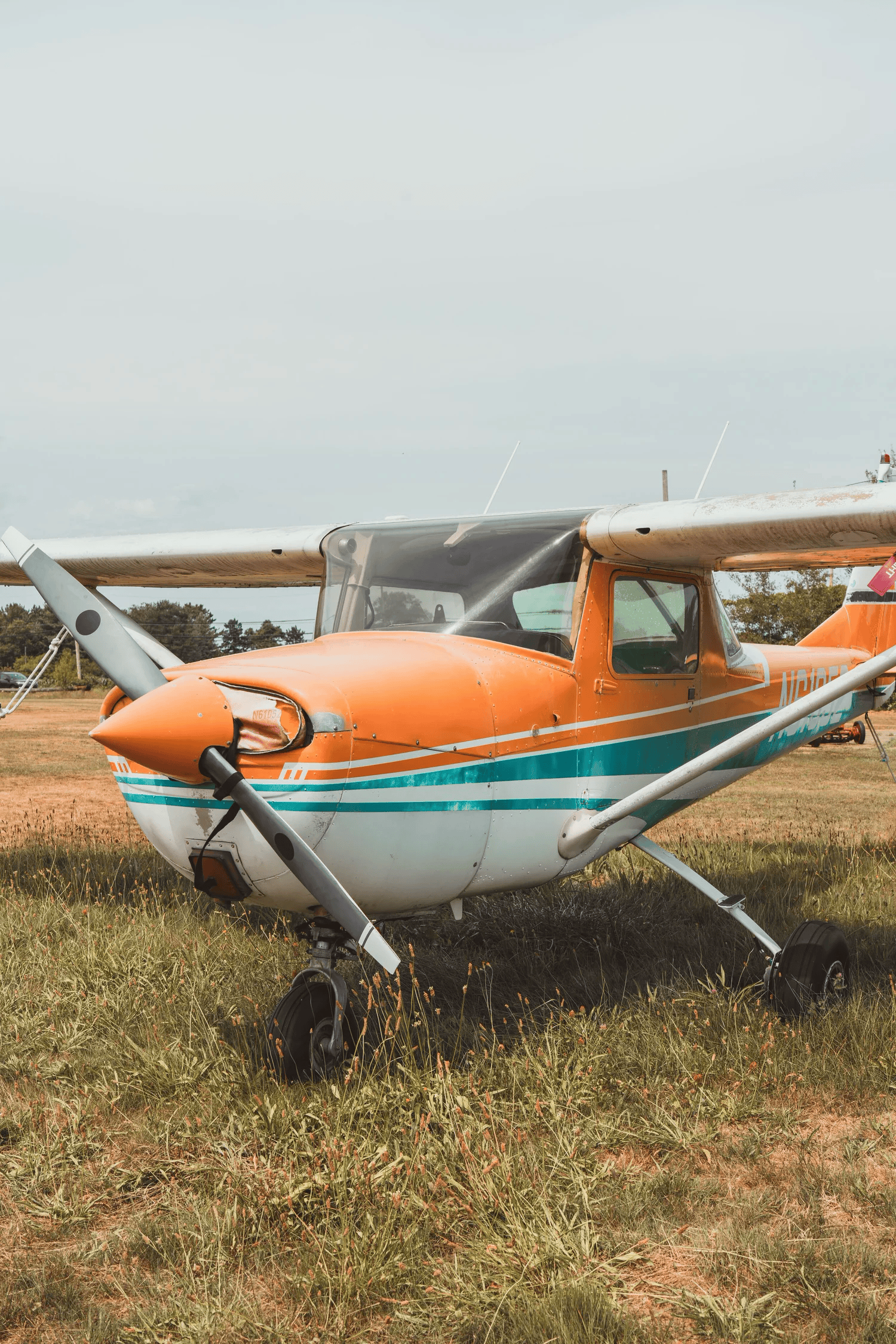 Full-color frontal photograph of a vintage propeller plane's nose and teal-striped fuselage
