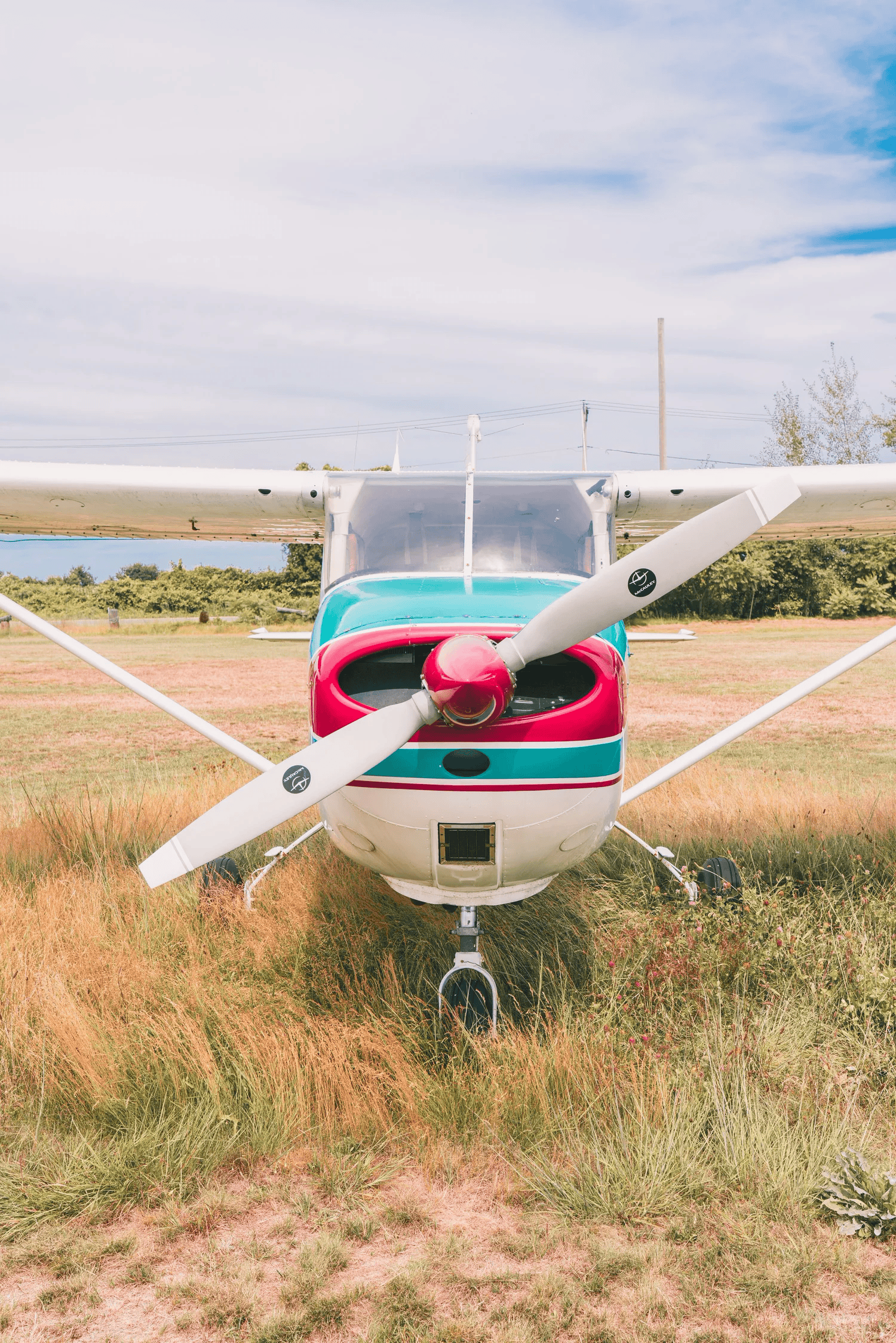 Full-color photograph of a vintage propeller plane's wing and red-and-teal tail markings from below