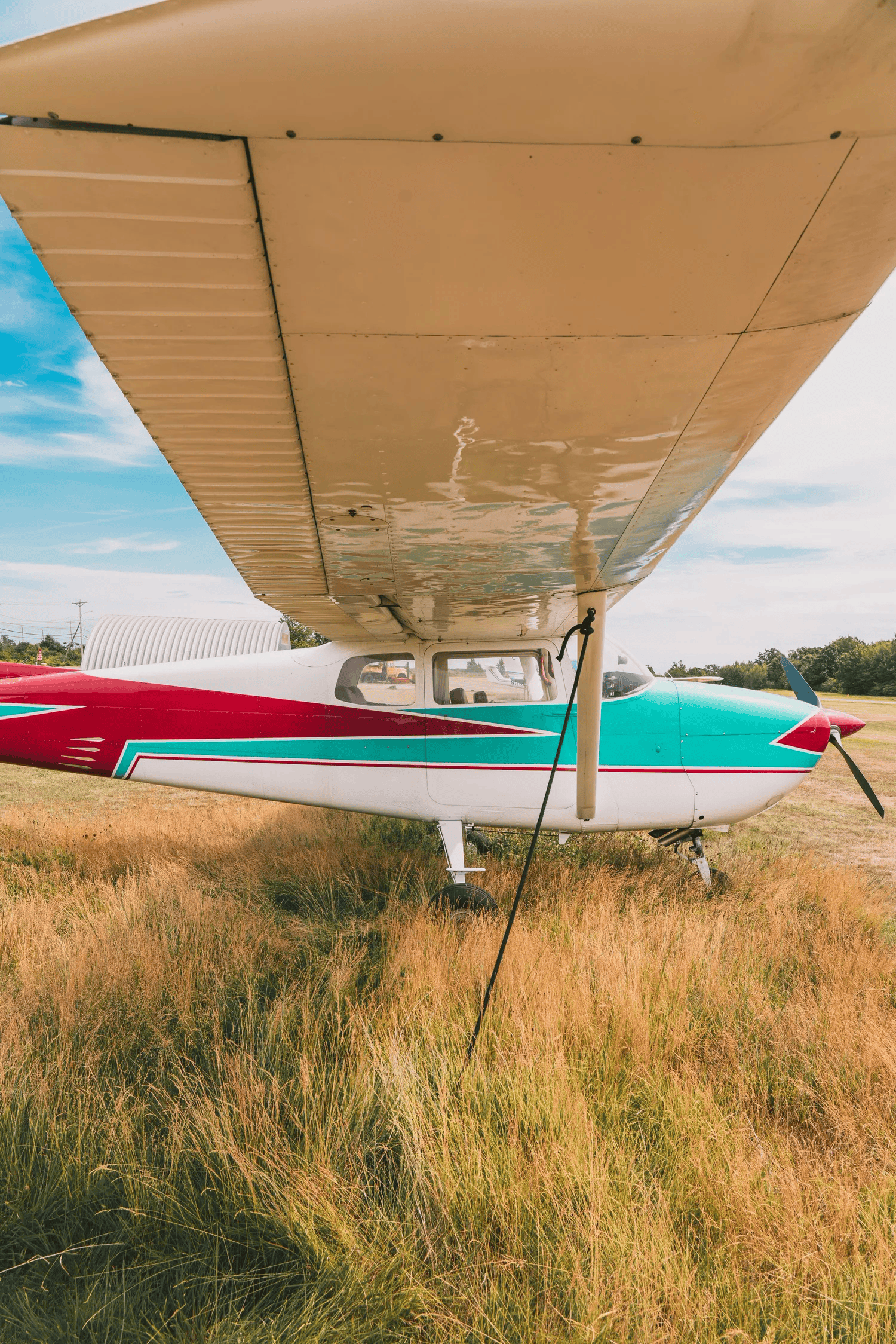 Full-color photograph of a weathered orange and white propeller plane parked on an airfield
