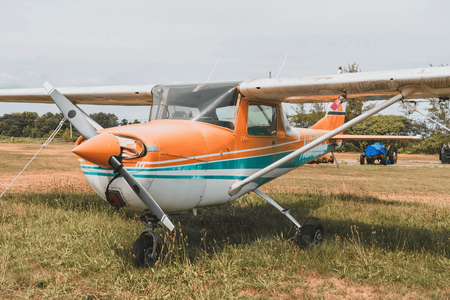 Full-color frontal photograph of a weathered propeller plane facing the camera in a grass field